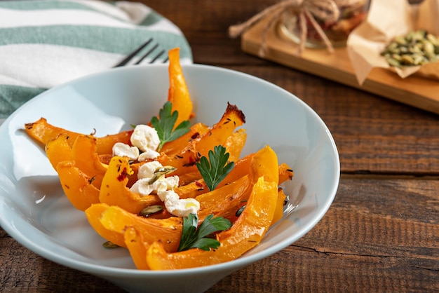 Baked pumpkin slices with cottage cheese in blue plate on wooden background autumn seasonal recipes with pumpkin