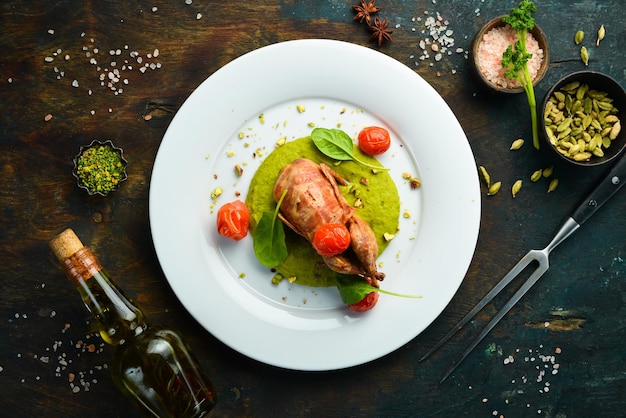 Baked quail in bacon with spinach hummus on a white plate Top view Rustic style