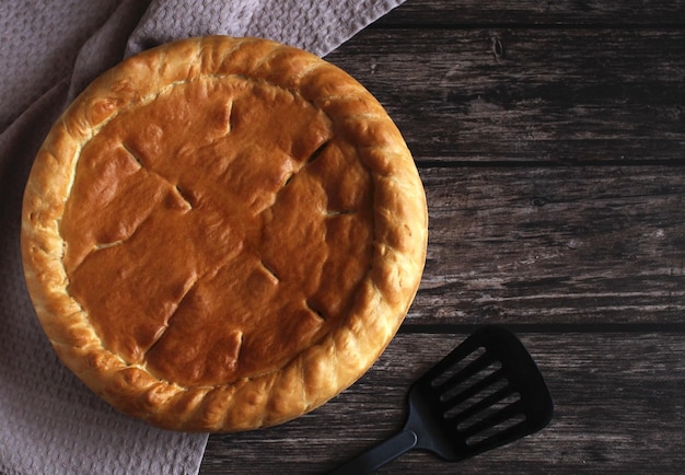 Baked round cake with filling on a wooden background top view