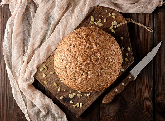 Baked round rye bread with sunflower seeds on a textile napkin