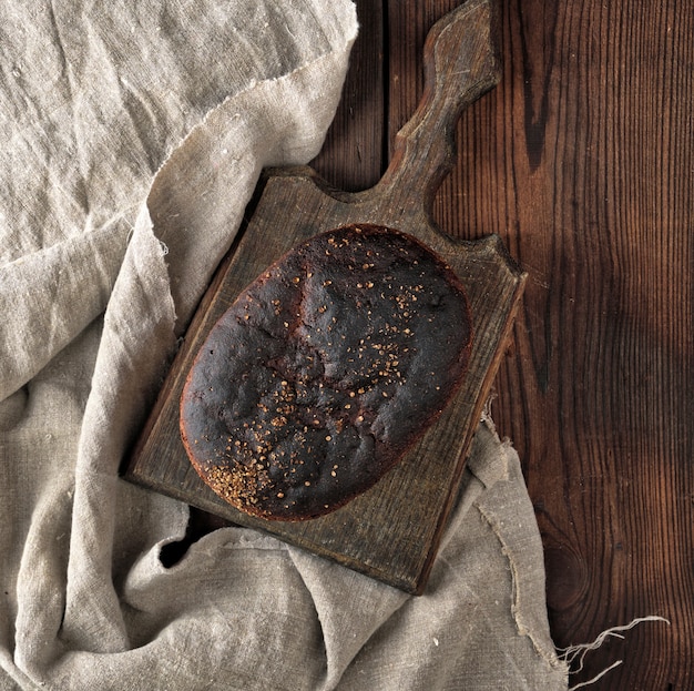 Baked rye bread on a gray linen napkin, brown wooden table