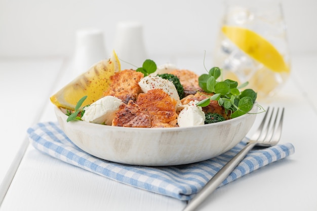 Baked salmon fillet salad with fresh vegetables, cream cheese, lemon, and microgreens. Healthy eating. Ketogenic diet. Close-up.