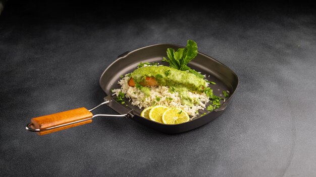 Baked salmon fillet with basmati rice in oven with spinach sauce served in dish isolated on table top view of arabic food