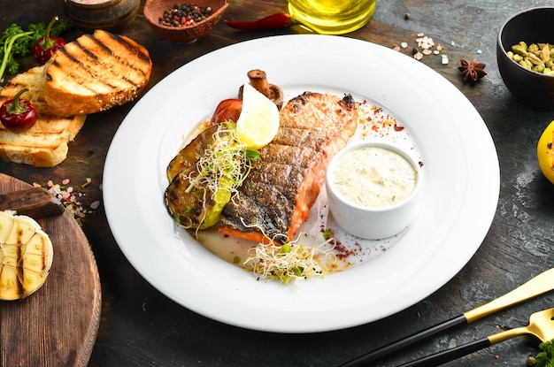 Baked salmon fillet with grilled vegetables on a plate Top view