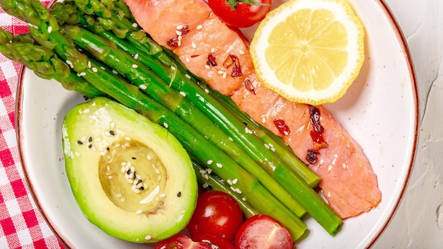 Baked salmon garnished with asparagus and tomatoes with avocado Top view Food recipe background Close up