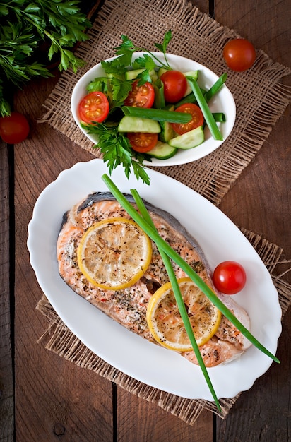 Baked salmon steak with herbs, lemon and salad