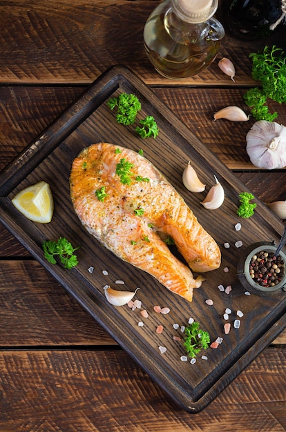 Baked salmon steak with herbs on wooden cutting board Grilled salmon with salt and pepper