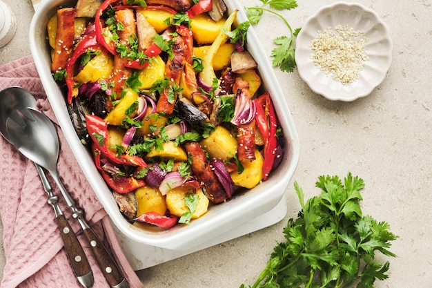 Baked sausage and vegetables peppers zucchini tomatoes red onion and eggplant with sesame and cilantro served hot from oven on baking tray Traditional lunch dish BBQ Sausage jersey tray bake