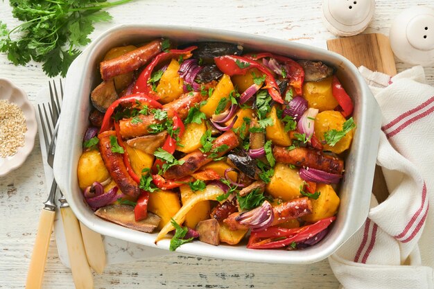 Baked sausage and vegetables peppers zucchini tomatoes red onion and eggplant with sesame and cilantro served hot from oven on baking tray Traditional lunch dish BBQ Sausage jersey tray bake