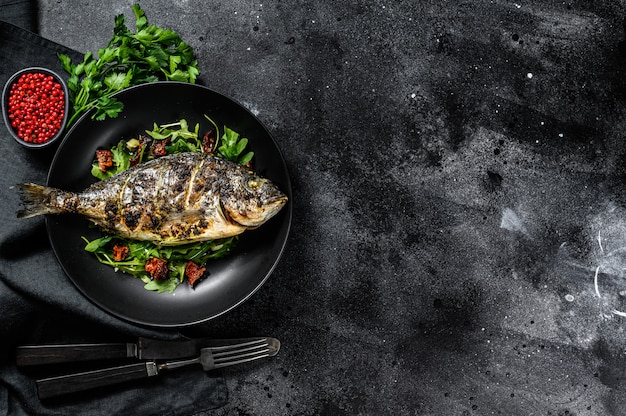 Baked sea bream fish with arugula salad and tomatoes. top view. Copy space