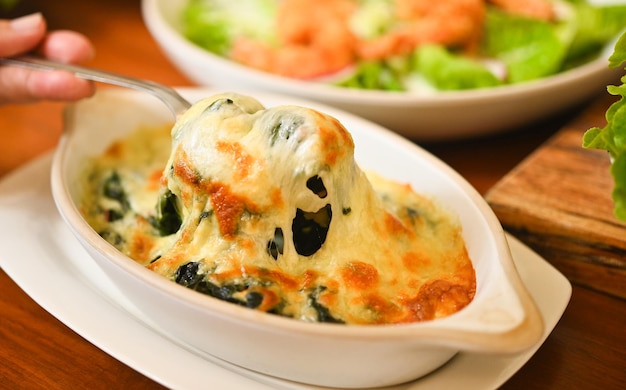 Baked spinach with cheese in a hot ceramic bowl on a wooden table