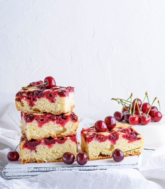 Baked square pieces of a biscuit pie with cherries 