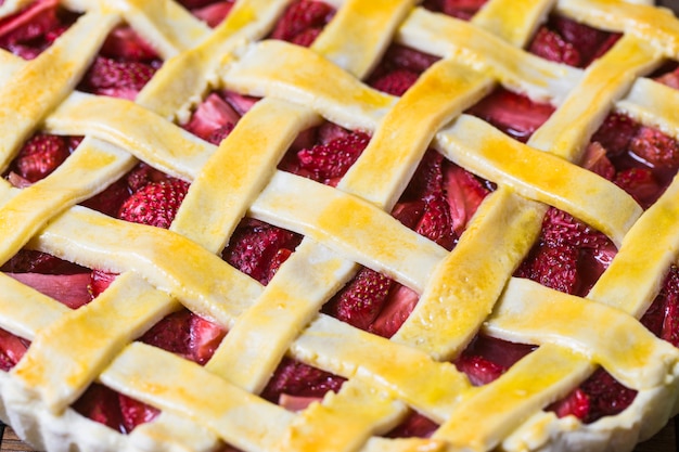 Baked strawberry pie cake sweet pastry on rustic wooden table background