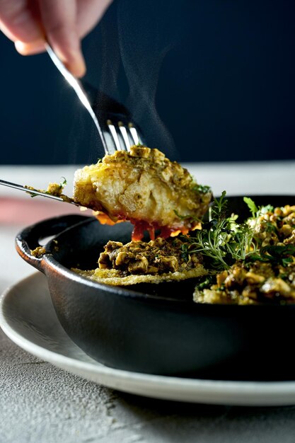 Baked and stuffed eggplants are cut with a knife and fork Concrete background Vegetarian dish