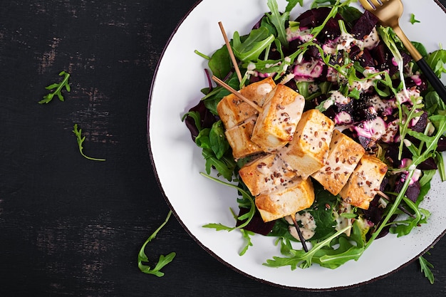 Baked tofu skewers in sauce and beet salad arugula with vegetable yogurt sauce Healthy vegan food concept Healthy food Top view flat lay