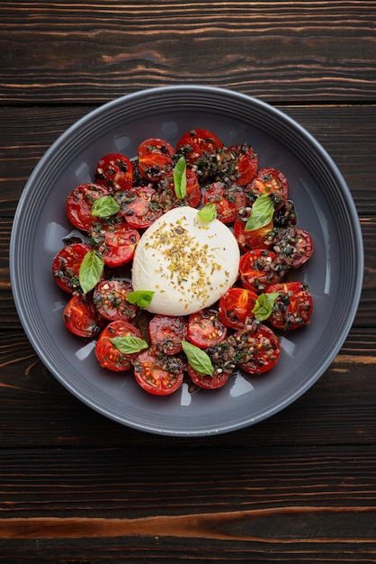 Baked tomatoes with mozzarella cheese on a wooden background