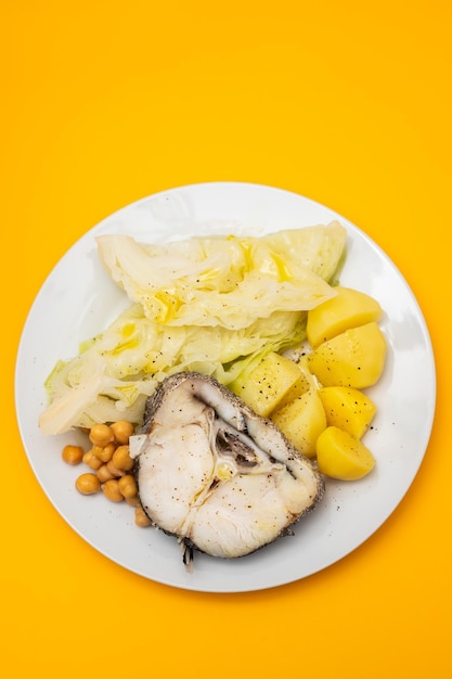 Baked vegetables with boiled fish on white plate