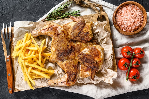 Baked whole chicken with potatoes. Black background. Top view