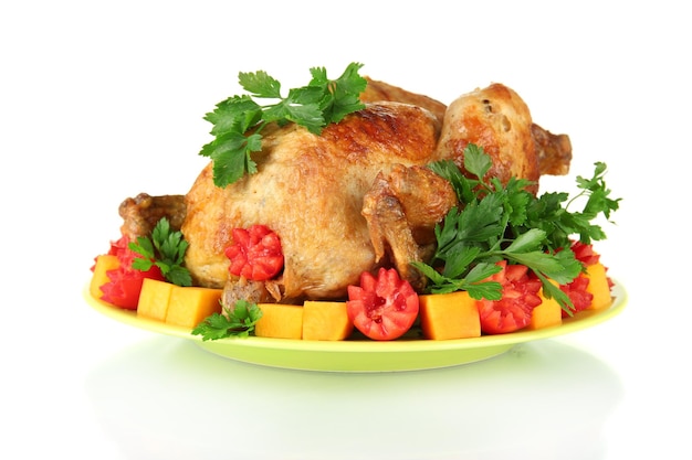 Baked whole chicken with vegetables on a green plate isolated on white