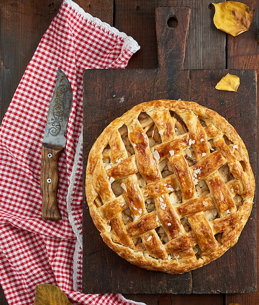 Baked whole round apple pie on a rectangular old brown board