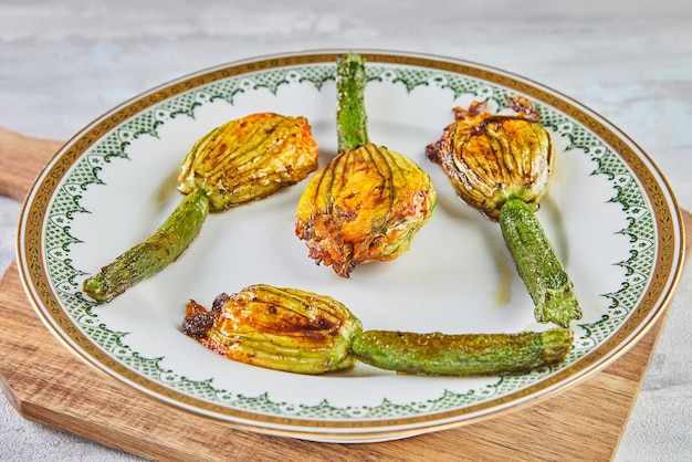 Baked zucchini or courgette flowers with parmesan cheese in casserole dish italian appetizer