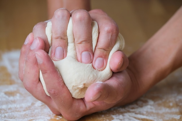 Baker crumples a lump of dough in his palms