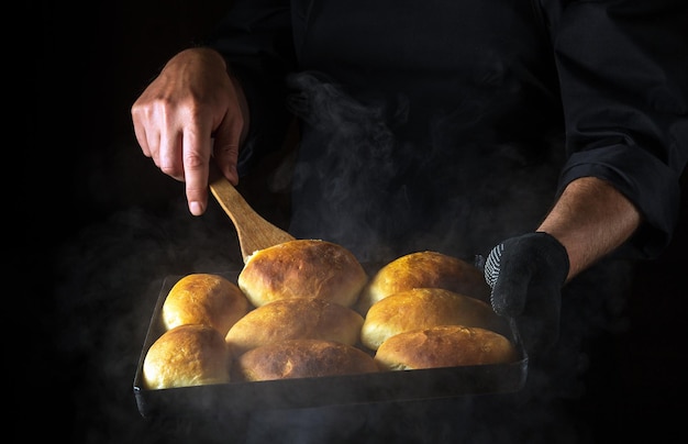 The baker flips the pies on a hot baking sheet The concept of making hamburger buns Black space for menu or recipe