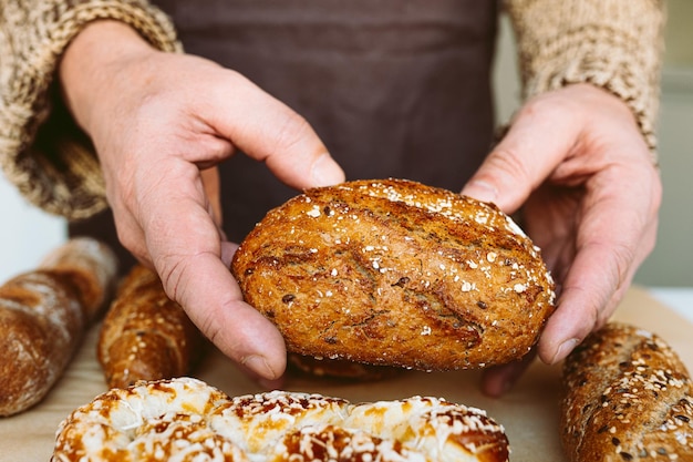 A baker holds a loaf of bread with sesame seeds on it.