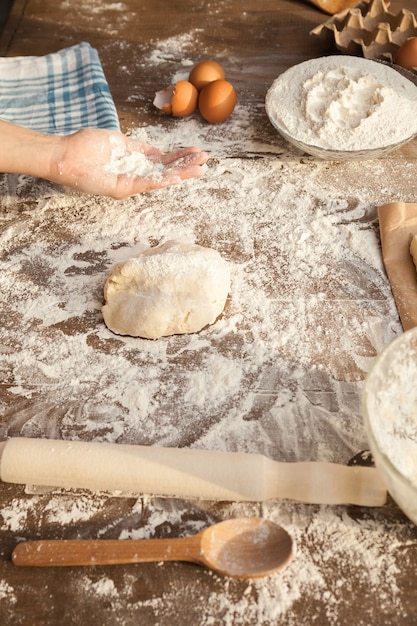 Baker is holing flour on his palm. With all ingredients on table. Side view.