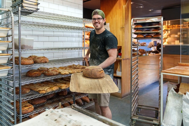 Baker Skilled worker with bread peel ready to bake batches of hearty loaves in bustling bakery