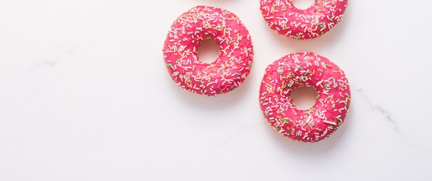 Bakery branding and cafe concept  frosted sprinkled donuts sweet pastry dessert on marble table background doughnuts as tasty snack top view food brand flat lay for blog menu or cookbook design