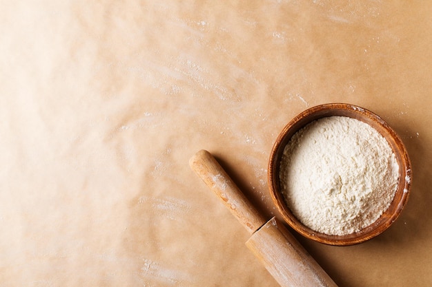 Bakery brown beige background with roll and flour flat lay