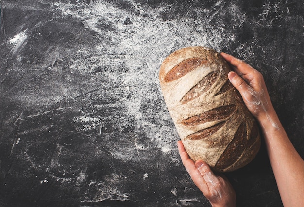 Photo bakery concept with bread and man hands on black background flat lay