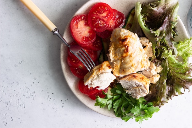 Baking chicken breast with cream cheese sauce with salad, tomatoes and grilled zucchini