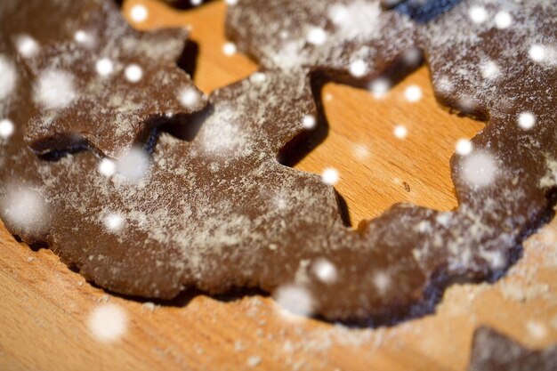 baking, cooking, christmas and food concept - close up of gingerbread dough, molds and flour on wooden cutting board from top