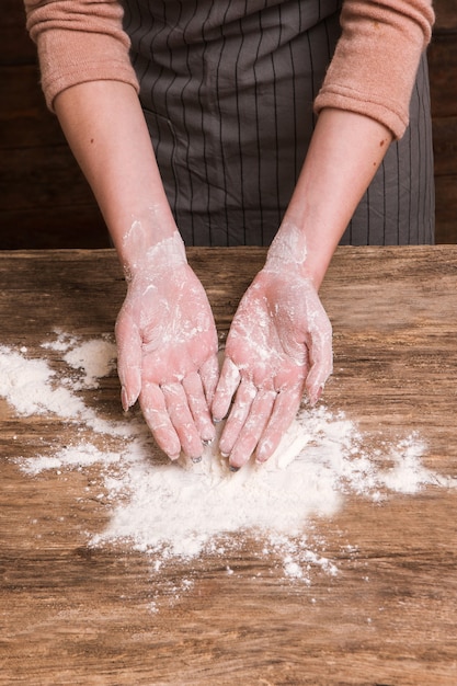 Baking craftsmanship. Woman hands making a dough from flour on wooden surface. Business bakery food industry concept