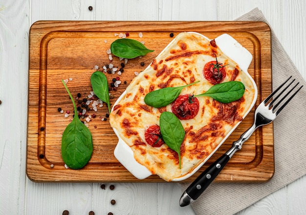 Baking dish with tasty vegetable lasagna on wooden background