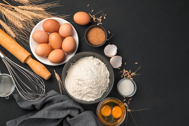 Baking ingredients on a black background flour eggs sugar