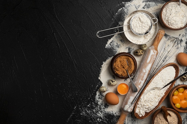 Baking ingredients for dough on black background, top view