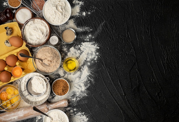 Baking ingredients for dough on black background, top view