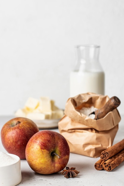 Baking ingredients for homemade apple cake or pie flour eggs milk sugar butter and spices on white background with copy space