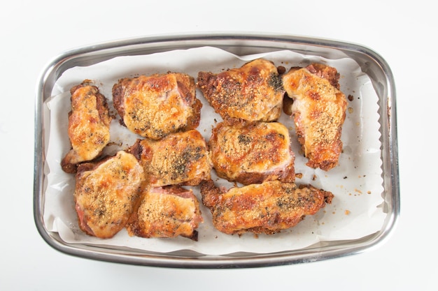 Baking pan with pieces of roasted chicken covered in cheese