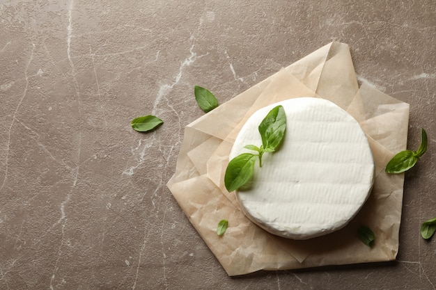 Baking paper with camembert cheese and basil on gray background