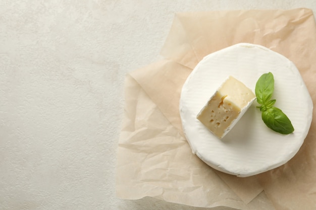 Baking paper with camembert cheese on white textured background