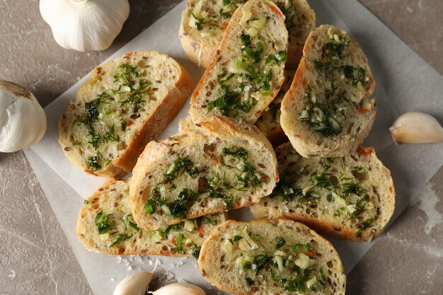 Baking paper with toasted garlic bread on grey