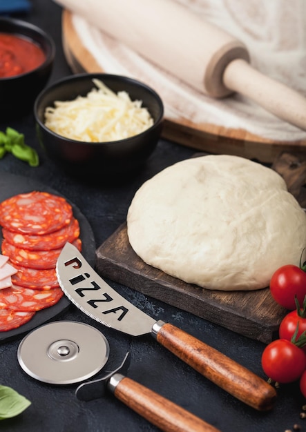 Baking of pepperoni pizza with raw dough salami spicy chorizo with wheel cutter and