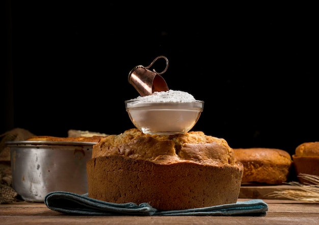 Baking powder in glass jar over traditional cake, all scene over rustic wood with cakes and baking dish in the background.