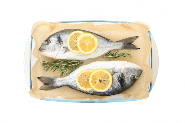 Baking tray with Dorado fishes, lemon and rosemary isolated on white