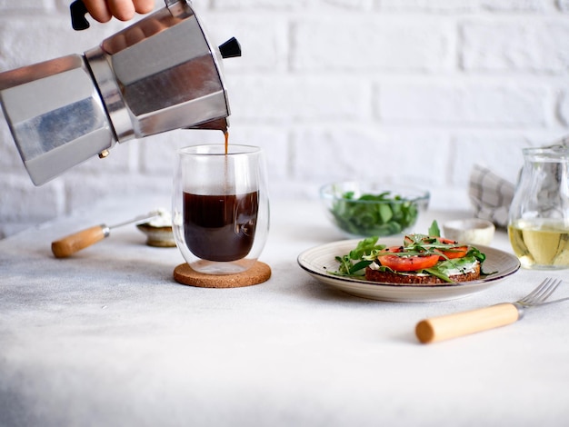 Balanced breakfast of sandwich with cheese tomatoes green and pouring hot coffee on light background Diet food