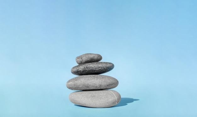 Balanced pebble stones for spa treatments on blue background The balancing cairn symbol of harmony tranquility and relaxation concept of meditation Stack of spa hot stones